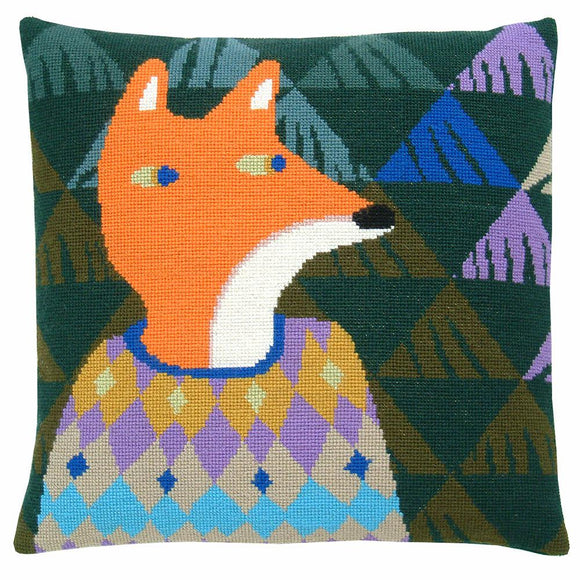 Cross stitch cushion cover with a fox wearing a yellow, purple, blue and fawn diamond-patterned jumper on a background of dark green, moss green, pale green, blue and purple triangles.